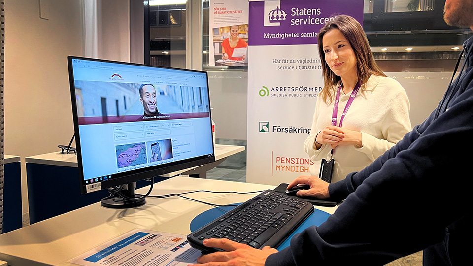 Servicehandläggare vid en dator där Migrationsverket visas i webbläsaren. 